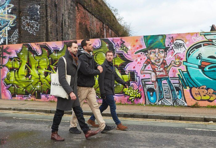 Andaz London Liverpool Street: Three gay men cross street in Shoreditch near colorful graffiti. Best gay hotels in London, gay travel advice.