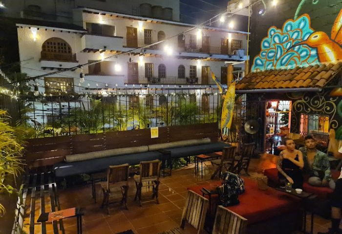 Puerto Vallarta gay bar patio at night. Outdoor seating, string lights, and colorful mural. A popular gay travel destination.