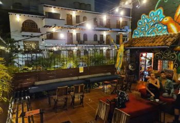 Puerto Vallarta gay bar patio at night. Outdoor seating, string lights, and colorful mural. A popular gay travel destination.