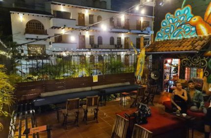 Puerto Vallarta gay bar patio at night. Outdoor seating, string lights, and colorful mural. A popular gay travel destination.