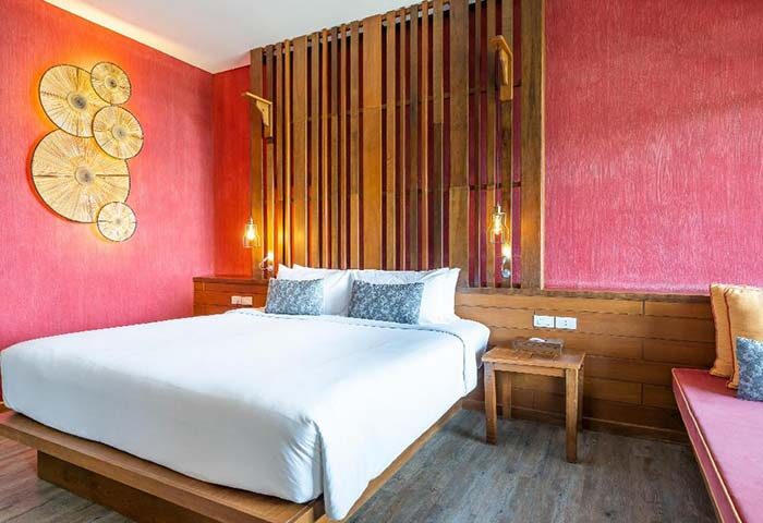 Ao Prao Resort, Koh Samet: Stylish hotel room interior. Gay-friendly travel destination with a comfortable bed, wooden decor, and pink walls.