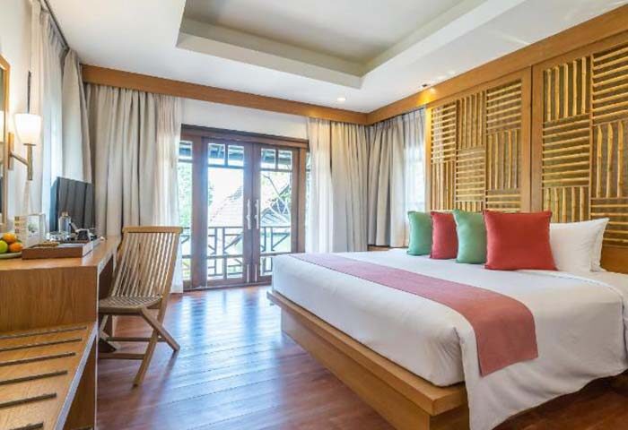 Ao Prao Resort, Koh Samet: Gay-friendly hotel room featuring a king-size bed, balcony, wooden furniture, and colorful pillows. Relaxing getaway.