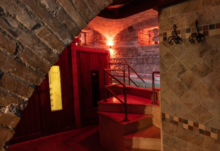Apollion Sauna Rome: Gay sauna's interior with brick arch, red-lit stairs, and tiled walls. A unique spa experience for gay men in Rome.