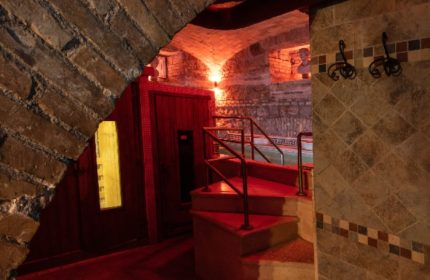 Apollion Sauna Rome: Gay sauna's interior with brick arch, red-lit stairs, and tiled walls. A unique spa experience for gay men in Rome.