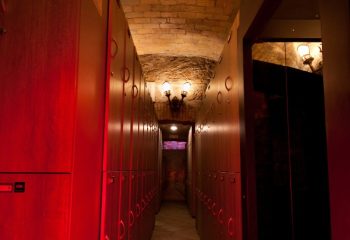 Hallway of Apollion Sauna Rome, a gay sauna. Lockers line the walls under a brick archway. Travel advice for gay men.