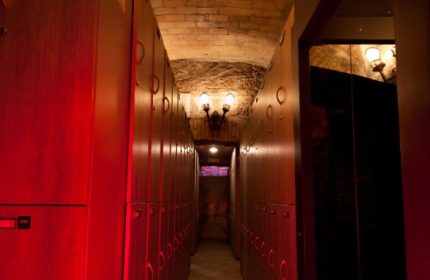 Hallway of Apollion Sauna Rome, a gay sauna. Lockers line the walls under a brick archway. Travel advice for gay men.