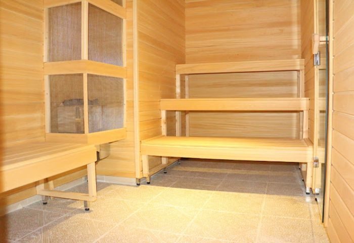 Interior of Apolo Sauna, a gay sauna in Torremolinos. Wooden benches line the walls, with a sauna heater visible behind a protective screen.