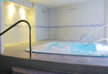 Apolo Gay Sauna in Torremolinos: Indoor jacuzzi with handrails, tiled walls, and steps. A relaxing spa experience for gay travelers.