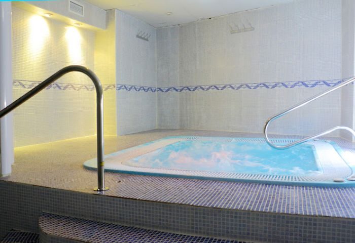 Apolo Gay Sauna in Torremolinos: Indoor jacuzzi with handrails, tiled walls, and steps. A relaxing spa experience for gay travelers.