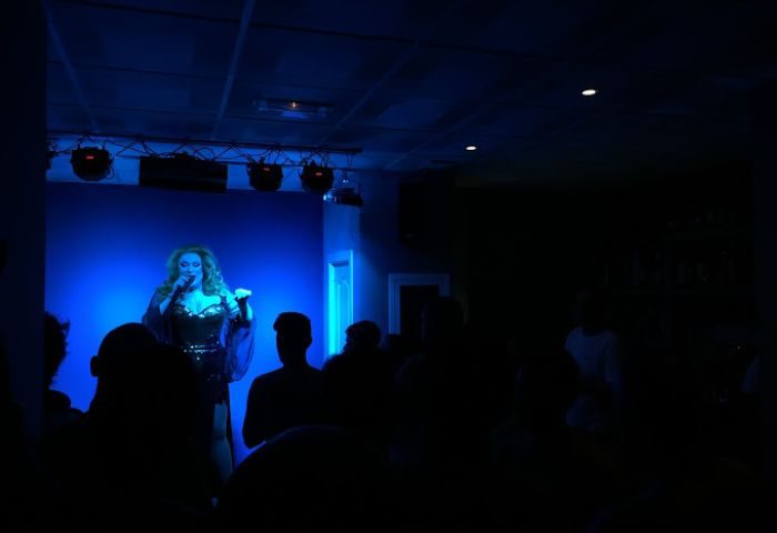 Apolo Cabaret gay sauna in Torremolinos show. Drag queen performing on stage with blue lighting in front of an audience. Gay travel.