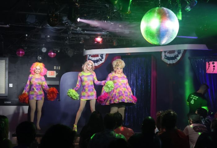 Aqua Bar Key West gay party: Drag queens perform on stage at a nightclub. Disco ball and crowd visible. Gay travel advice.