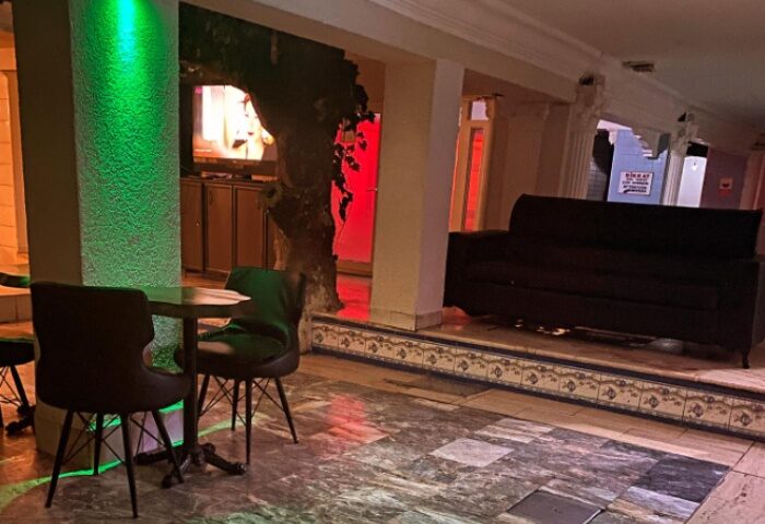 Aquarius Sauna Istanbul lounge area. Table with chairs, couch on raised platform, and ambient lighting. Gay travel advice.