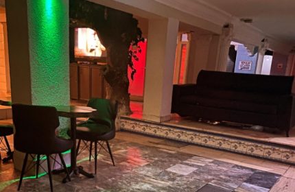 Aquarius Sauna Istanbul lounge area. Table with chairs, couch on raised platform, and ambient lighting. Gay travel advice.