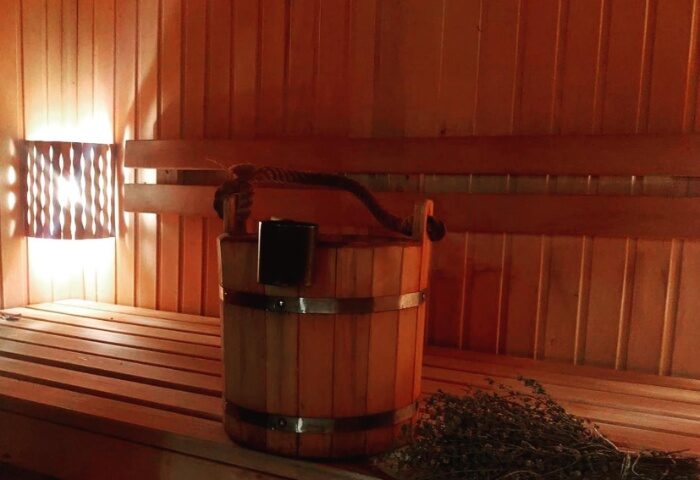 Aquarius Sauna Istanbul: Interior view of a wooden sauna with bucket, ladle, and bench. Gay travel destination for relaxation.