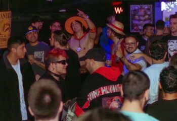 Gay nightlife in Barcelona: Arena Xperience gay club scene. Crowd of diverse men enjoying the party, some in costumes. Vibrant atmosphere.