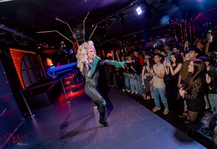 Drag queen performing at Arena Xperience Gay Club in Barcelona. Crowd of gay men watching the show, taking photos. Nightlife scene.