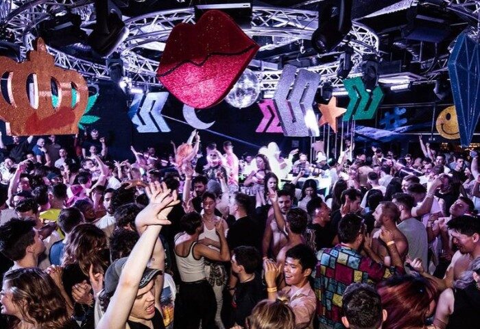 Arq Sydney: Gay men dance at a crowded nightclub with colorful decorations. Nightlife scene, travel advice for LGBTQ+ visitors.