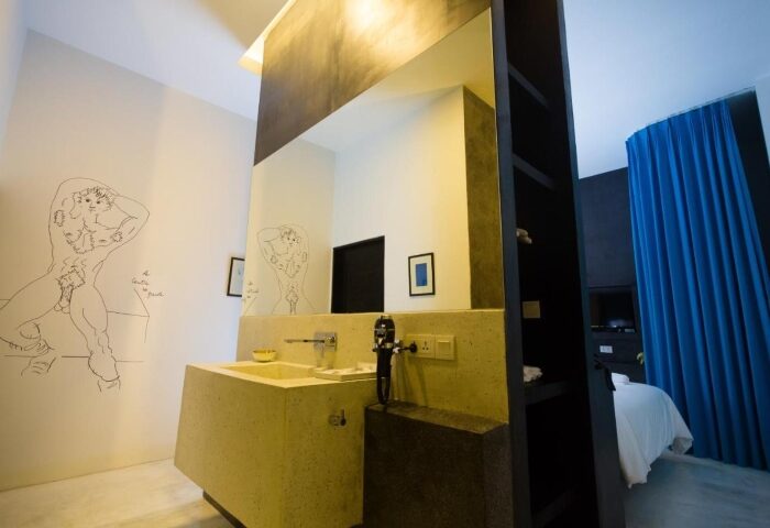 Arthur & Paul men-only hotel bathroom. Modern design with a sink, mirror, and a drawing of a nude man on the wall. Gay travel.