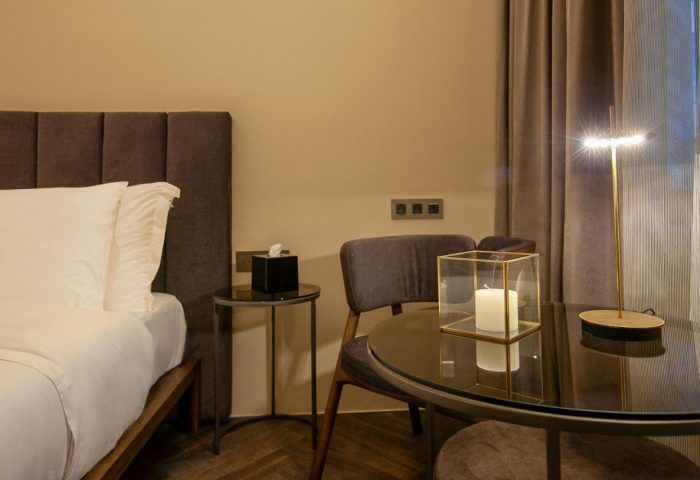 Athens 1890 Hotel room detail. Gay-friendly adults-only hotel with bed, table, chair, and lamp. Modern design and cozy atmosphere.