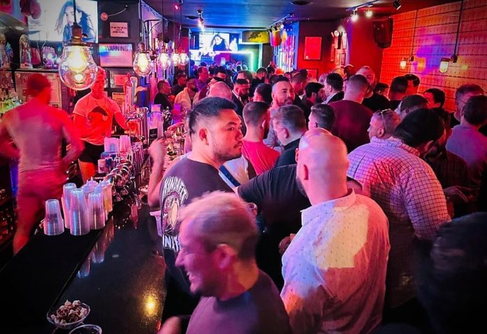 Crowded Atlas Social Club in New York. Interior view of the gay bar with many men socializing. Gay travel advice in NYC.