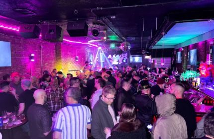 Atmosphere gay bar in Andersonville, Chicago. Patrons enjoy live music in a crowded, colorful space with exposed brick and disco balls.