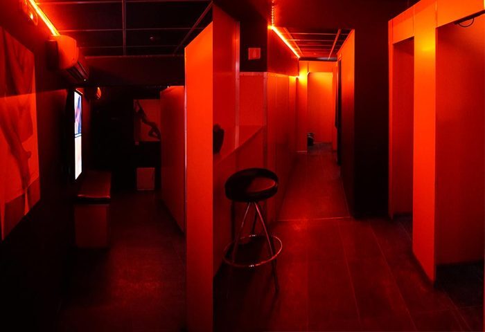 Attraxx Athens: Interior of a gay sauna with red lighting, cubicles, and a stool. Gay travel advice for Athens, Greece.