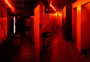 Attraxx Athens: Interior of a gay sauna with red lighting, cubicles, and a stool. Gay travel advice for Athens, Greece.