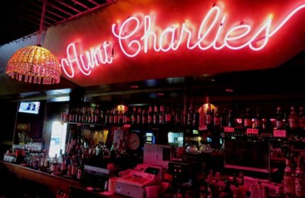 Aunt Charlie's Lounge bar in San Francisco. Neon sign above a fully stocked bar. Popular gay bar and travel destination.