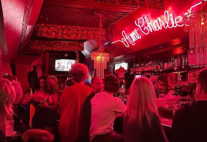 Aunt Charlie's Lounge, San Francisco. A neon sign glows above patrons at this popular gay bar. Red lighting and chandeliers add to the ambiance.