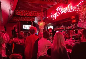 Aunt Charlie's Lounge, San Francisco. A neon sign glows above patrons at this popular gay bar. Red lighting and chandeliers add to the ambiance.