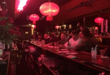 Aunt Charlie's Lounge in San Francisco. Gay bar interior with red lighting, lanterns, and patrons at the bar. Gay travel destination.