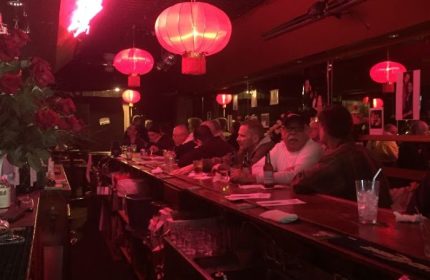 Aunt Charlie's Lounge in San Francisco. Gay bar interior with red lighting, lanterns, and patrons at the bar. Gay travel destination.