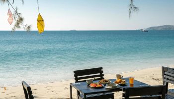 Avatara Resort Koh Samet beachfront dining. Table set for breakfast on the beach. Popular gay hotel destination.