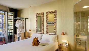 Axel Hotel Barcelona room. Gay adults-only hotel near gay bars. Room with bed, backpack, laptop, mirrors, and bathroom. Urban spa hotel.