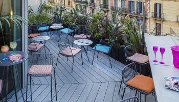 Axel Hotel Barcelona rooftop bar seating area. Gay adults only hotel with urban spa. Cocktails, chairs, and city view.