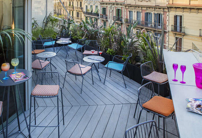 Axel Hotel Barcelona rooftop bar seating area. Gay adults only hotel with urban spa. Cocktails, chairs, and city view.