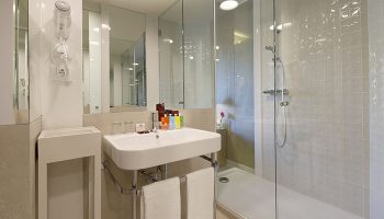 Bathroom at Axel Hotel Barcelona, a gay adults-only urban spa. Modern design with walk-in shower, sink, and toiletries. Most booked gay hotel.