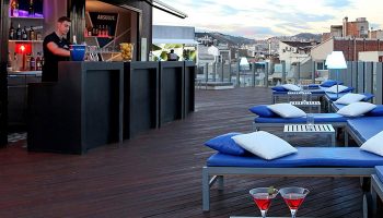 Axel Hotel Barcelona rooftop pool bar. Gay adults-only hotel with cocktails, sunbeds, city views. Popular gay travel destination.