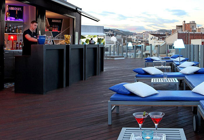 Axel Hotel Barcelona rooftop pool bar. Gay adults-only hotel with cocktails, sunbeds, city views. Popular gay travel destination.
