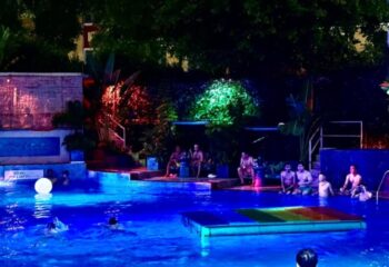 Azure Pool Bar, Ho Chi Minh. Gay men enjoy a night swim at the rooftop pool bar. Rainbow float, tropical plants, and colorful lights.