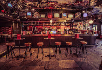 BAR Soho, a top gay bar in London near Leicester Square. Interior view with stools, bar, and vintage TVs. Great spot for gay men's travel.