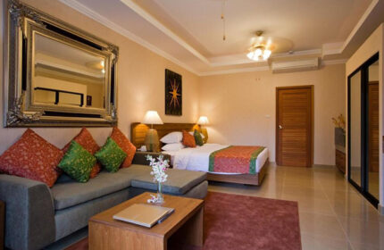 Baan Souy Resort's exclusive gay hotel room. Features a bed, couch, mirror, and table. Ideal for gay travel and relaxation.