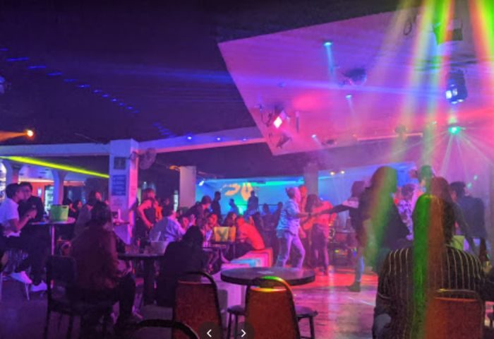 Interior of Baby Club, a gay bar in Mexico. People dance under colorful lights. Gay travel nightlife scene.