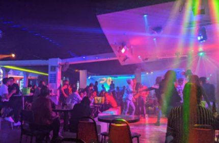 Interior of Baby Club, a gay bar in Mexico. People dance under colorful lights. Gay travel nightlife scene.
