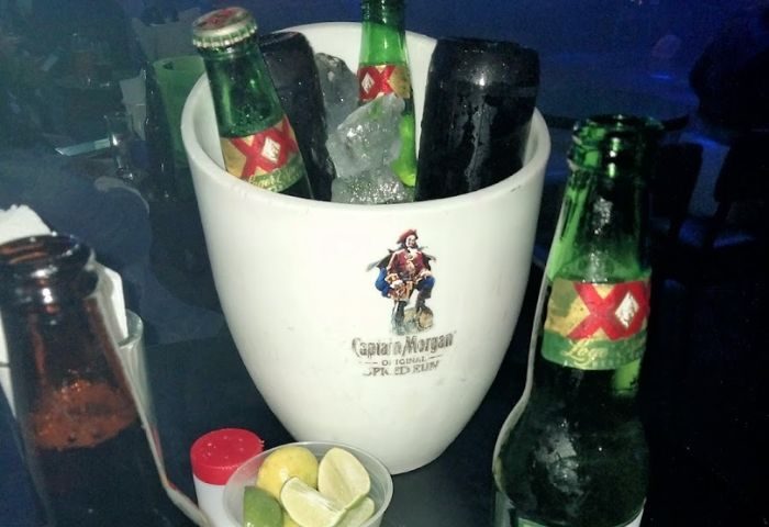 Ice bucket with XX Lager at a gay bar in Mexico. Limes and salt are nearby. Captain Morgan logo on bucket. Gay travel advice.