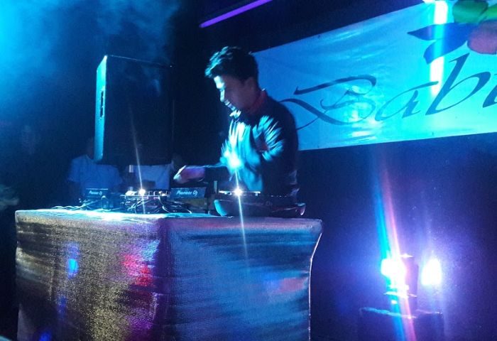 DJ at Baby Club, a gay bar in Mexico, mixing music under blue lights. Gay nightlife scene, travel advice for gay men.