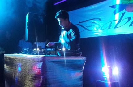 DJ at Baby Club, a gay bar in Mexico, mixing music under blue lights. Gay nightlife scene, travel advice for gay men.