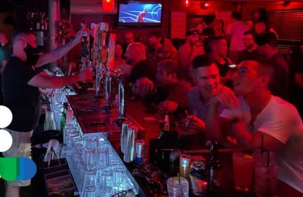 Bacchus Waikiki gay bar party in Honolulu. Bartender serving drinks at a crowded bar. Gay nightlife in Hawaii. Men socializing, red lights.