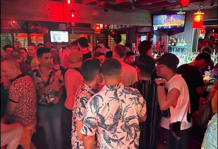 Party at Bacchus Waikiki gay bar in Honolulu. Crowded scene with men socializing, drinking at the bar. Gay travel advice.