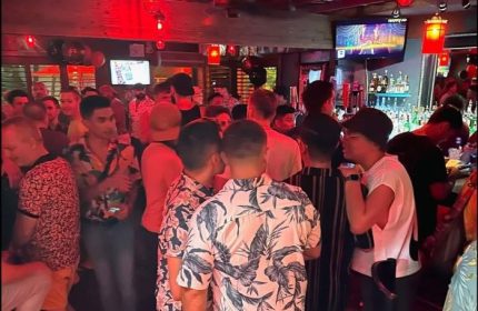 Party at Bacchus Waikiki gay bar in Honolulu. Crowded scene with men socializing, drinking at the bar. Gay travel advice.